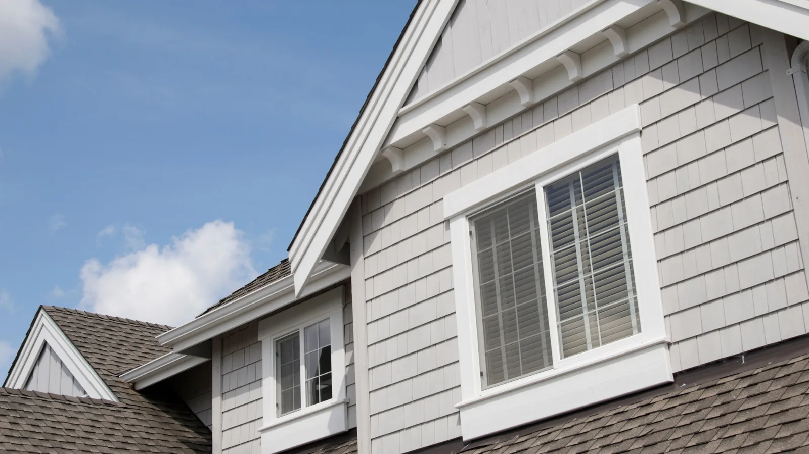 White trimmed gables and windows above a brown asphalt shingle roof